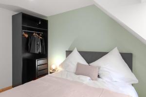 - une chambre avec un lit blanc et des oreillers blancs dans l'établissement Das Wiesenhaus: Wohnen direkt am Rhein, à Cologne