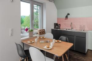 - une cuisine avec une table en bois, des chaises et un évier dans l'établissement Das Wiesenhaus: Wohnen direkt am Rhein, à Cologne