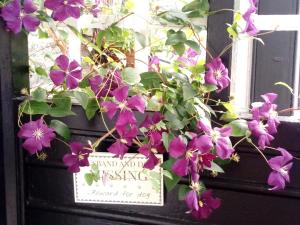 a bunch of purple flowers on a door with a sign at Puddle Duck Lodge – Adults Only in Bowness-on-Windermere