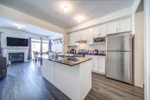 a kitchen with white cabinets and a stainless steel refrigerator at Executive Town Home-Mountain View-Historic Snowbridge Village, Walking Distance to the Resort in Collingwood