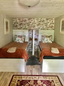 two beds in a room with a brick wall at The Old Henhouse in Tollarp
