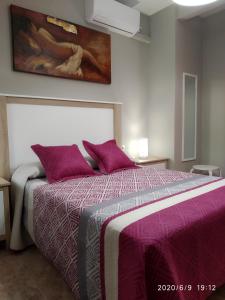 - une chambre dotée d'un lit avec des draps violets et un tableau dans l'établissement Casa Miguel y Petra, à Peal de Becerro