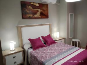 Un dormitorio con una cama con almohadas moradas y una pintura en Casa Miguel y Petra, en Peal de Becerro