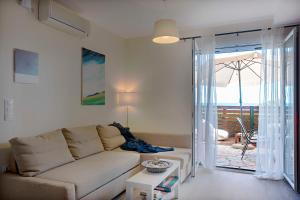 een woonkamer met een bank en een glazen schuifdeur bij Ammos Beach House in Glyfada