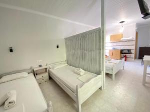 Habitación blanca con 2 camas y cocina en Faros Studios, en Ligia