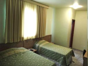 ein Hotelzimmer mit 2 Betten und einem Fenster in der Unterkunft HF Minas Hotel in Vespasiano