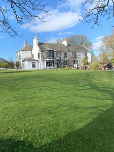 une grande pelouse devant une maison dans l'établissement Torrs Warren Country House Hotel, à Stoneykirk