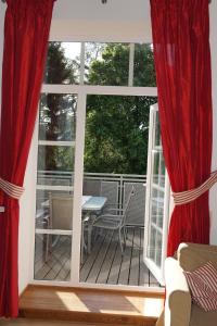 un porche cubierto con cortinas rojas y una mesa en Auberge Tabarz Zimmerberg en Tabarz