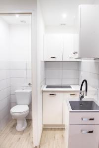 a white bathroom with a toilet and a sink at Pokoje Gościnne in Kołobrzeg