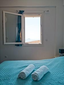 a bedroom with two towels on a bed with a window at Αλός αήρ suites in Kithnos