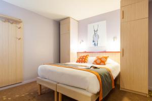 een slaapkamer met een groot bed met oranje kussens bij Résidence Pierre & Vacances Electra in Avoriaz