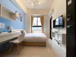 um quarto com uma cama, uma escrivaninha e uma televisão em Adagio Hostel em Taichung