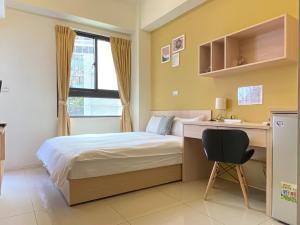 a bedroom with a bed and a desk and a chair at Adagio Hostel in Taichung