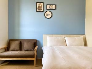 a bedroom with a bed and a chair and a clock at Adagio Hostel in Taichung