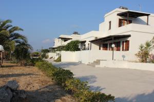 a white house with palm trees in front of it at Galini in Agia Irini Milos