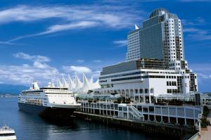 um navio de cruzeiro atracado ao lado de um edifício alto em Pan Pacific Vancouver em Vancouver