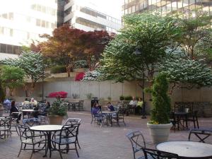 Holiday Inn Washington Capitol-National Mall, an IHG Hotel في واشنطن: يجلس الناس على الطاولات في ساحة مع الأشجار