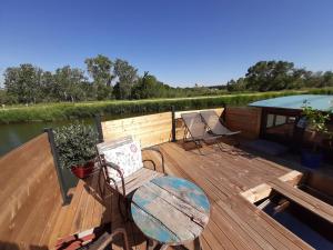 une terrasse en bois avec une table et des chaises ainsi qu'une piscine dans l'établissement Péniche La Belle Aimée, à Aigues-Mortes