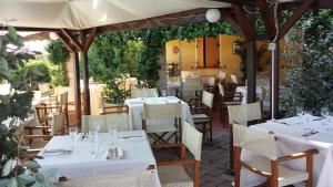 un restaurante con mesas blancas y sillas bajo una sombrilla en B & B La Rotta, en Rávena