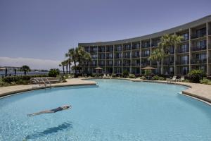 a person swimming in a pool in front of a hotel at Pirates' Bay Marina II in Fort Walton Beach
