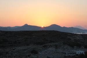a sunset in the desert with mountains in the background at Galini in Agia Irini Milos