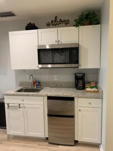 una cucina con armadi bianchi, lavandino e forno a microonde di Zen Oasis a Tampa