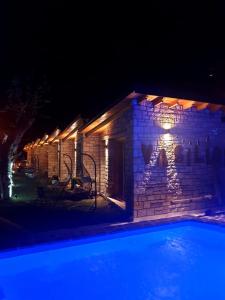 ceglany budynek z basenem w nocy w obiekcie Palermiti Luxury Rooms w mieście Himara