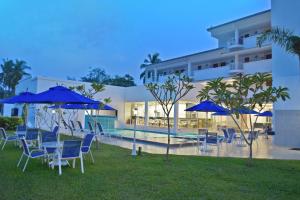 a hotel with blue chairs and umbrellas next to a pool at AVI Pangkor Beach Resort in Pangkor