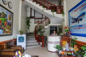 a woman standing at a counter in a building with stairs at Ahoj Guest House in Ha Long