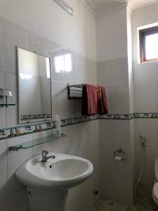 een witte badkamer met een wastafel en een spiegel bij Tulip Mui Ne in Phan Thiet