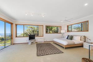 a bedroom with a bed and a tv and windows at Seascape @ 19 Pindari - privacy, space, views in Dunbogan