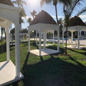 a white gazebo and a pool with palm trees at Hotel Aldea del Bazar & Spa in Puerto Escondido