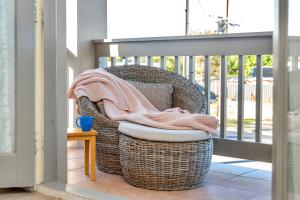 a wicker chair sitting on a porch with a towel at The Lighthouse - Port Willunga - C21 SouthCoast Holidays in Port Willunga