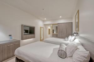 a bedroom with a white bed and white walls at Duxton Hotel Perth in Perth