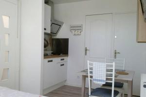 eine weiße Küche mit einem Tisch und einem Schreibtisch in der Unterkunft Studio Cosy Douillet et Fonctionnel in Savigny-le-Temple