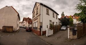 ein weißes Haus auf einer Straße mit parkenden Autos in der Unterkunft 55m² 2 Zimmer-Monteurswohnung mit 4 einzelnen Betten in Nieder-Saulheim