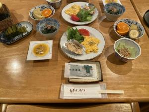 una mesa de madera con platos de comida. en Villa Kubota, en Nozawa Onsen