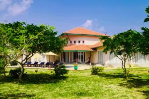 una casa con un patio con sillas y árboles en The Beach house by Kay Jay Hotels, en Pasikuda