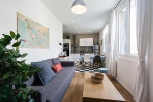 a living room with a blue couch and a kitchen at Appartement 2 chambres hypercentre Saint Nazaire in Saint-Nazaire