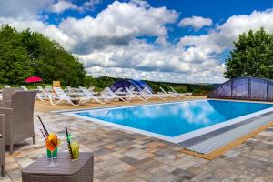 a swimming pool with chairs and a table with drinks at Panorama Berghotel Wettiner Höhe in Seiffen