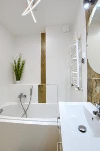 a white bathroom with a tub and a sink at Apartamenty Wybrzeże Laguna II in Ustronie Morskie