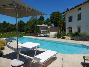 a pool with two chairs and an umbrella next to a table and sidx at B&B Bionzo16 in Calosso