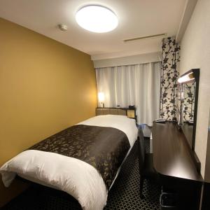 a hotel room with a bed with a desk and a window at APA Hotel Toyohashi-Ekimae in Toyohashi