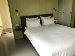 een groot wit bed met witte kussens in een kamer bij B&B In het Voorhuys in Zuidlaren
