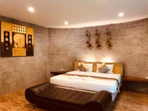 a bedroom with a large bed and a leather couch at Nao Ta Chuang in Thung Song