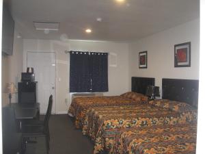 Habitación de hotel con 2 camas, escritorio y ventana en Western Motel, en Lovell