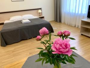 a vase with pink flowers on a table in a bedroom at VESK Svečių Namai in Druskininkai