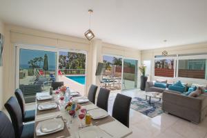 a dining room with a table and a living room at Shaye Front Line Villa in Protaras