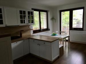 a kitchen with white cabinets and a table and windows at Apartman Kristof in Vysoke Tatry - Tatranska Lomnica.