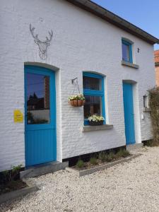 een wit huis met blauwe deuren en ramen bij Wetterdelle in Heers